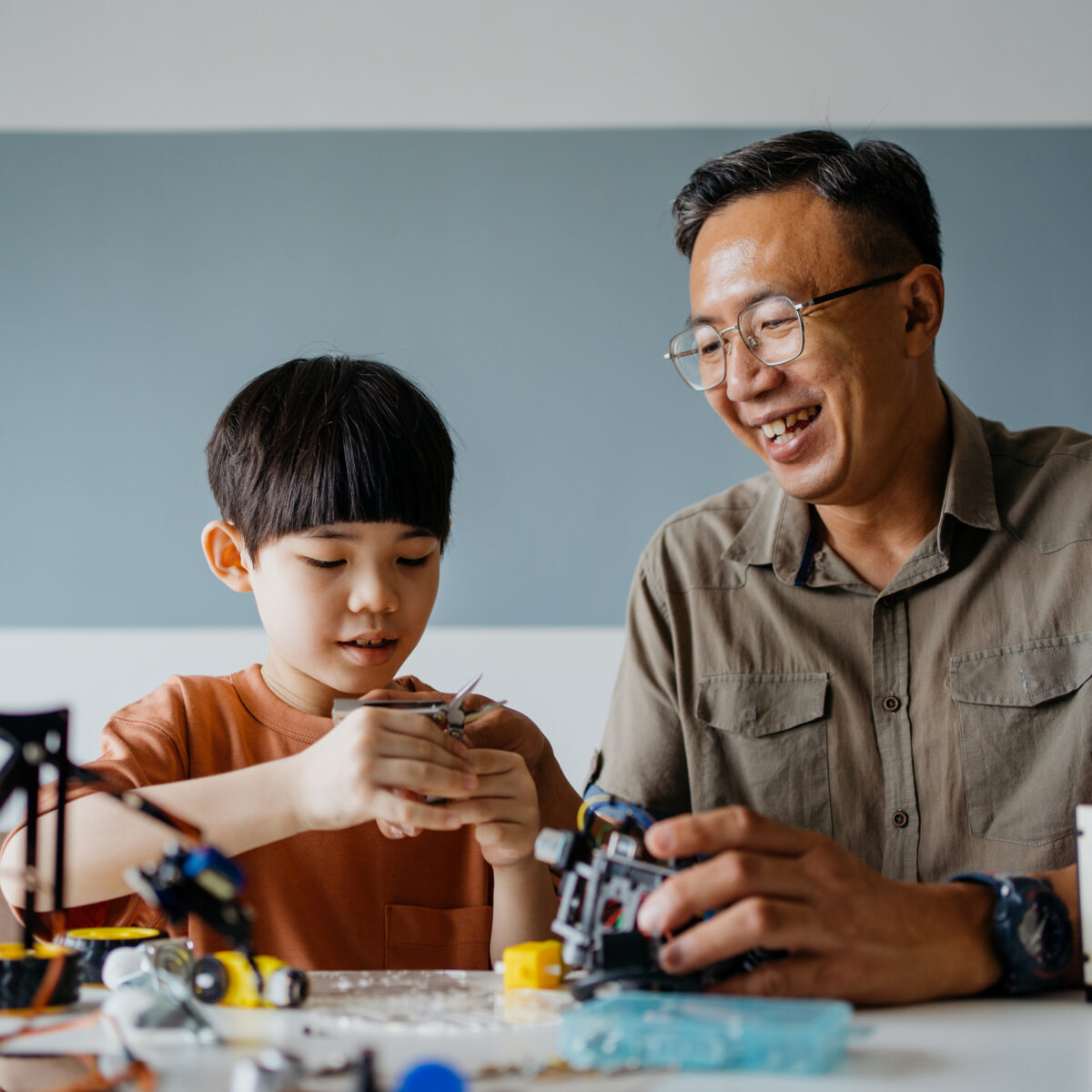Father and son building robot toy at home