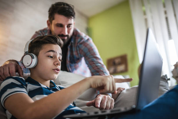 Smiling father and son using digital gadgets in living room